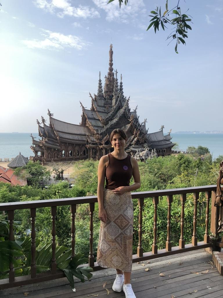 Ein junges Mädchen steht in einem Sarong vor einem Tempel in Thailand
